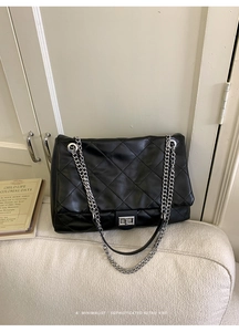 Close-up of quilted black leather tote featuring silver metal chain and twist lock detail