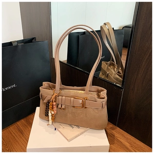 Gros plan d'un sac bandoulière en daim marron avec boucle et breloque en perles
