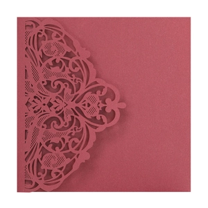 Macro detail of wine red laser-cut lace invitation card with intricate floral patterns