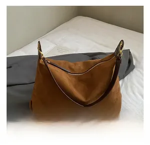 Détail du sac fourre-tout en daim marron avec crochets dorés et bandoulière en cuir