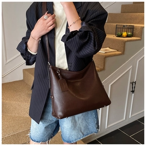 Detail of dark brown hobo shoulder bag featuring matte leather texture and leather tag
