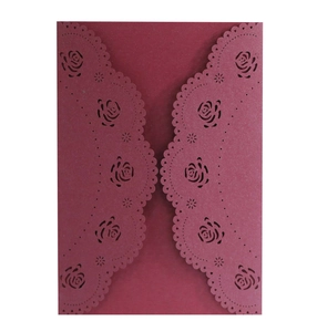 Macro view of laser-cut burgundy pearl paper wedding invitation with rose hollow patterns