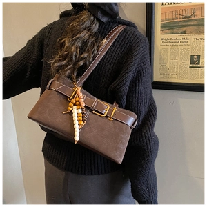 Vue latérale du sac bandoulière rétro en daim marron avec boucle et breloque en perles