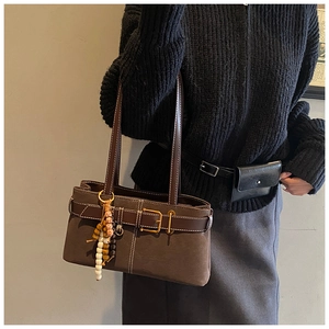 Détail d'un sac cabas vintage marron foncé avec boucles et pendentif en perles de bois