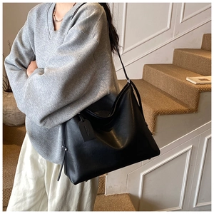 Close-up of large black leather tote bag featuring sleek metal rivets and brand tag