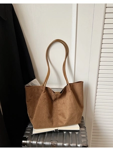 Détail d'un grand sac cabas en daim marron avec fines bandoulières et coutures précises