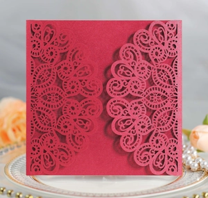 Detailed laser-cut wedding invitation shell with intricate floral lace pattern on red cardstock