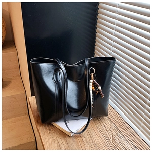 Detail of black glossy PU leather tote bag with vintage wooden beaded pendant