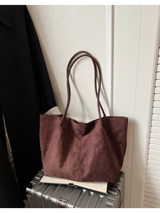 Détail du grand cabas en daim avec couture verticale sur une valise et un livre