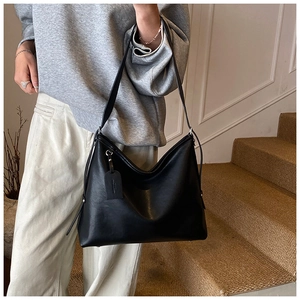 Detail of minimalist black large capacity crossbody bag with matte faux leather texture