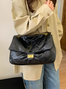 Classic black quilted tote bag with gold chain strap and turn-lock closure on model