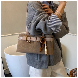 Détail du sac baguette marron rétro avec boucle vintage et pendentif perlé ethnique