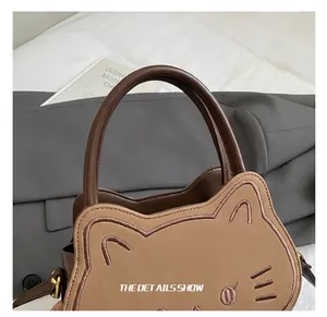 Dettaglio ravvicinato di una borsa a mano marrone a forma di gatto con ricamo e orecchie