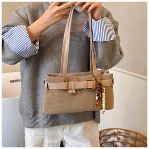 Détail du sac bandoulière vintage beige avec boucle décorative et breloque en perles de bois