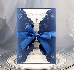 Detail of laser-cut navy blue wedding invitation with silk ribbon and rose patterns