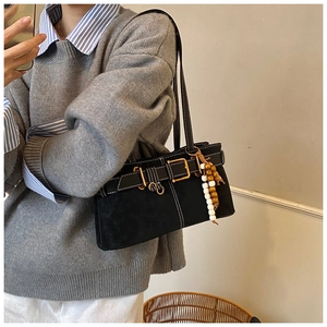 Détail du sac à bandoulière noir en daim avec boucles dorées et breloque en perles rétro