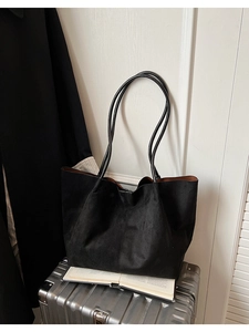 Détail d'un grand sac cabas en daim noir avec fines anses et doublure marron interne