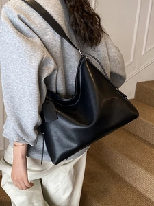 Minimalist black hobo shoulder bag with adjustable strap shown in a lifestyle setting