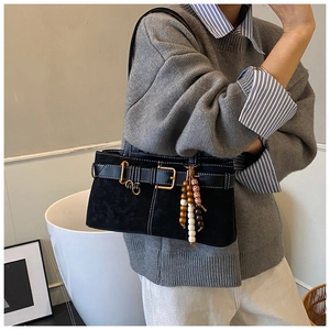 Détail d'un sac bandoulière en daim noir avec boucle décorative et perles en bois colorées
