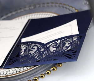 Detail of laser-cut navy blue wedding invitation with European lace pattern on pearlescent paper