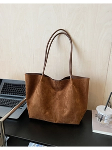 Détail d'un grand sac cabas en daim marron avec fines bandoulières pour le bureau