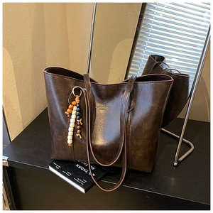 Close-up of retro dark brown tote bag with matte texture and decorative beaded keychain