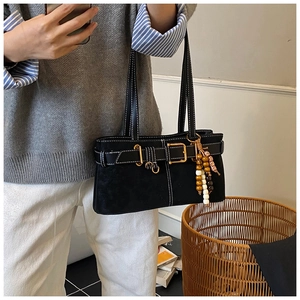 Détail d'un sac à bandoulière en daim noir avec boucle dorée et breloque en perles de bois