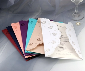Macro detail of laser-cut rose hollow patterns on colorful wedding invitation covers