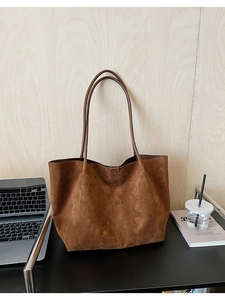 Gros plan détaillé de la texture du sac cabas en daim marron foncé avec coutures fines