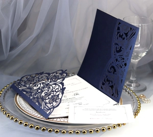 Detail of laser-cut navy blue wedding invitation with elegant floral lace texture