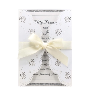 Detail of laser-cut rose hollow wedding invitation with elegant cream satin bow