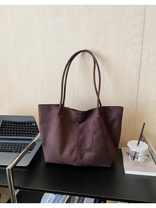 Sac fourre-tout en daim marron dans un bureau avec ordinateur et magazine