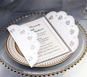 Laser cut rose lace wedding invitation with silver glitter frame on a glass plate