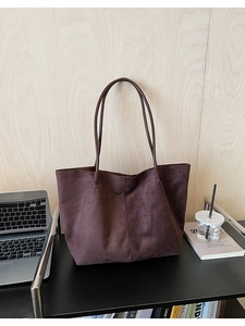 Détail d'un grand sac cabas en daim marron sur un bureau avec ordinateur et livres