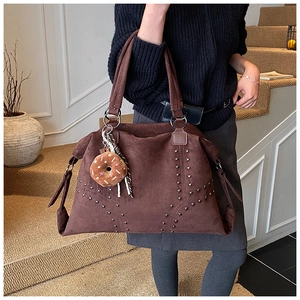 Detailansicht der dunkelbraunen Wildleder-Tote Bag mit Metallnieten und Anhängern