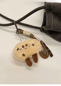Detail of furry biscuit monster plush pendant hanging on a brown pebbled leather bag