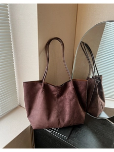 Sac cabas en daim marron foncé avec fines bretelles dans un décor de chambre épuré