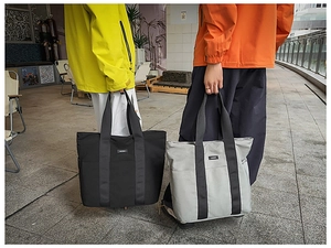 Close-up of minimalist tote bags in black and sage green with durable canvas texture