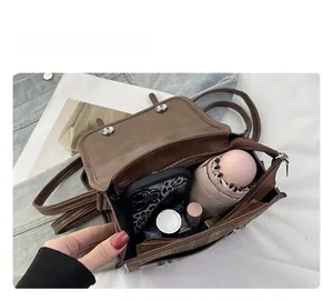 Détail de l'espace intérieur du sac bandoulière marron avec téléphone, parapluie et parfum
