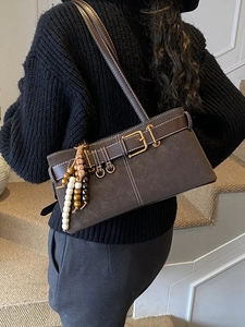 Sac porté épaule vintage marron avec boucle dorée et perles en bois sur un mannequin