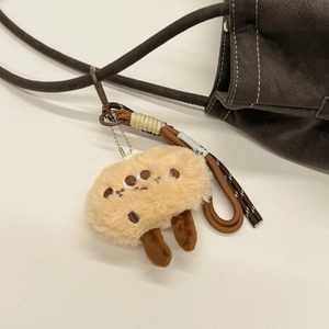 Macro detail of khaki plush charm with dark embroidery on a leather shoulder bag