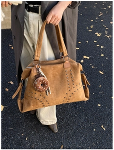 Detailansicht braune Wildledertasche mit Nieten vor Herbsthintergrund mit Ginkgoblättern