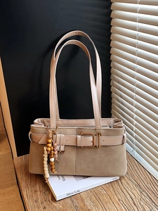 Sac à bandoulière rétro beige avec pampilles en bois et boucle sur un support en bois chic