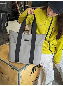 Detail of grey canvas tote bag with black wide strap and MOCOBAO label for daily commute