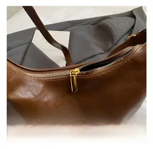 Nahaufnahme der goldenen Reißverschluss-Hardware an der braunen Leder-Eimertasche