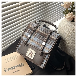 Detail of vintage brown leather bag with plaid pattern and cute bear embroidery patch