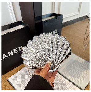 Macro shot of a silver shell-shaped evening bag with glossy wavy texture and metal chain