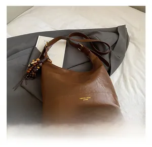 Nahaufnahme einer braunen Leder-Eimertasche mit Lychee-Struktur und Holzperlen