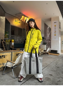 Macro shot of durable gray canvas tote bag with black straps in a street style setting