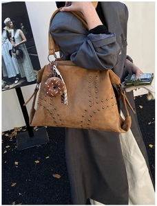 Gros plan d'un sac cabas en daim marron avec clous et breloque donut sur un mannequin